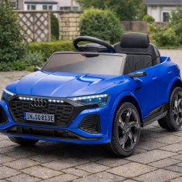 Niebieskie auto na akumulator Audi SQ8 dla dzieci stojące na podwórku z kostki brukowej