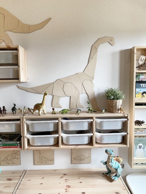 Drewniany regał dziecięcy z pojemnikami na zabawki oraz dekoracją ścienną dinozaura w pokoju dziecka