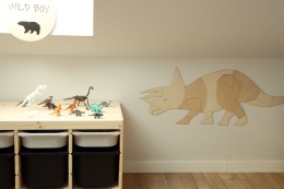 Drewniana dekoracja ścienna dinozaur triceratops w pokoju dziecka obok regału na zabawki