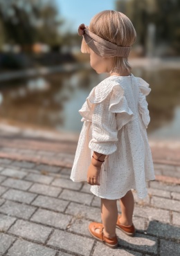Dziewczynka w sukience ecru z muślinu z falbankami widok z tyłu stylizacja outdoor