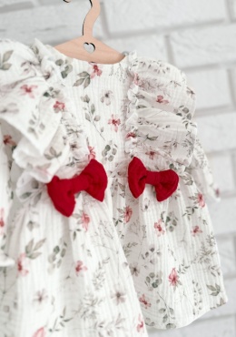Detal muślinowej sukienki dziewczęcej w kwiaty – falbanki i czerwona kokarda handmade