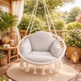Huśtawka bocianie gniazdo z jasnoszarą poduszką zawieszona na tarasie w stylu boho