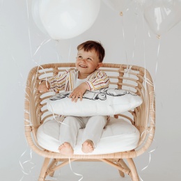 Dziecko siedzące na fotelu z poduszką newborn z nadrukiem niemowlęcia w jasnym wnętrzu