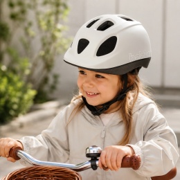 Dziewczynka w białym kasku rowerowym Bobike GO podczas jazdy na rowerze – lekki kask ochronny dla dzieci