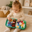 Dziecko bawiące się filcową książeczką sensoryczną Montessori rozwijającą zdolności manualne i koncentrację.
