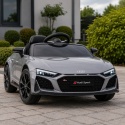 Srebrne Audi R8 na akumulator dla dziecka na podjeździe przed domem – sportowy samochód elektryczny z reflektorami LED