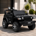 Czarny Jeep Rubicon na akumulator dla dzieci zaparkowany przed nowoczesnym domem