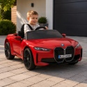 Czerwone auto na akumulator BMW i4 dla dziecka podczas zabawy na podjeździe przed domem