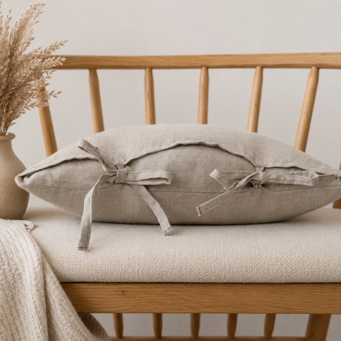 Poduszka lniana z troczkami LINEN Natural wykonana ze 100% lnu w naturalnym beżowo-szarym kolorze na drewnianej ławce