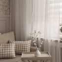 Biała firana Romantic w salonie z dekoracyjnymi poduszkami i subtelnym wzorem, elegancka dekoracja okna do nowoczesnych wnętrz