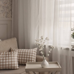 Biała firana Romantic w salonie z dekoracyjnymi poduszkami i subtelnym wzorem, elegancka dekoracja okna do nowoczesnych wnętrz