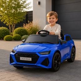 Niebieskie Audi RS6 na akumulator dla dziecka podczas zabawy przed nowoczesnym domem. Licencjonowany samochód elektryczny