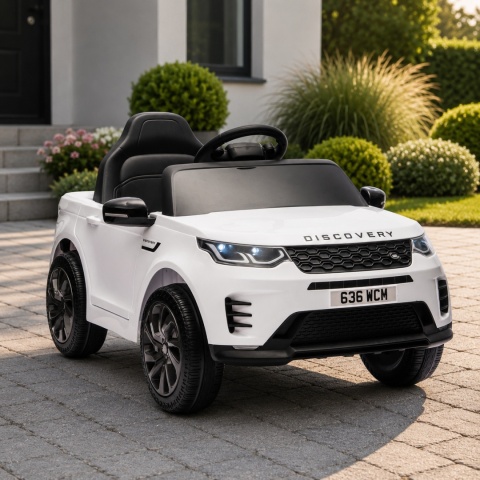 Biały Land Rover Discovery na akumulator dla dzieci zaparkowany przed domem w ogrodzie