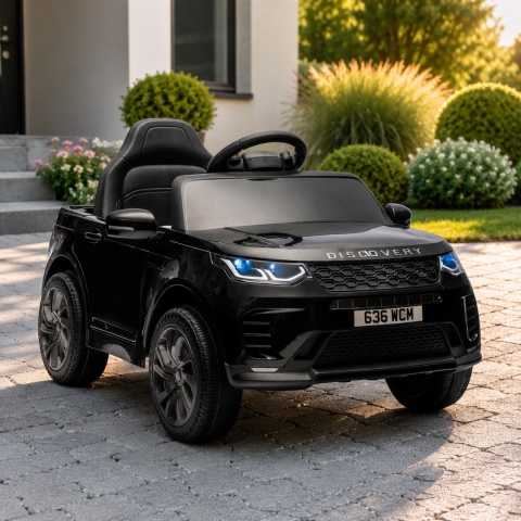 Czarny Land Rover Discovery na akumulator dla dzieci na podjeździe przed domem