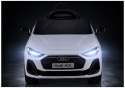 Białe Audi A5L na akumulator z włączonymi przednimi światłami LED – widok z przodu.