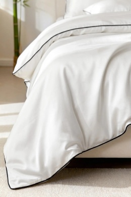 Biała pościel bambusowa premium z czarną bizą na łóżku