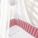 Ochraniacz do łóżeczka Glamour w kolorze brudnego różu, z miękkimi pionowymi panelami, w aranżacji z białym baldachimem.