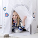 Dziewczynka w stroju astronautki bawi się w białym namiocie dziecięcym w kształcie rakiety kosmicznej