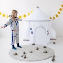 Dziewczynka w stroju astronautki bawi się obok namiotu rakiety kosmicznej w pokoju dziecięcym
