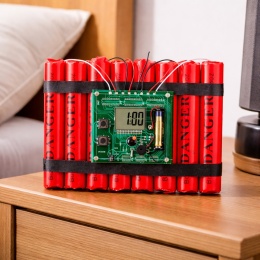 Urządzenie stylizowane na atrapę ładunku z czerwonymi cylindrami i wyświetlaczem elektronicznym umieszczone na stoliku nocnym